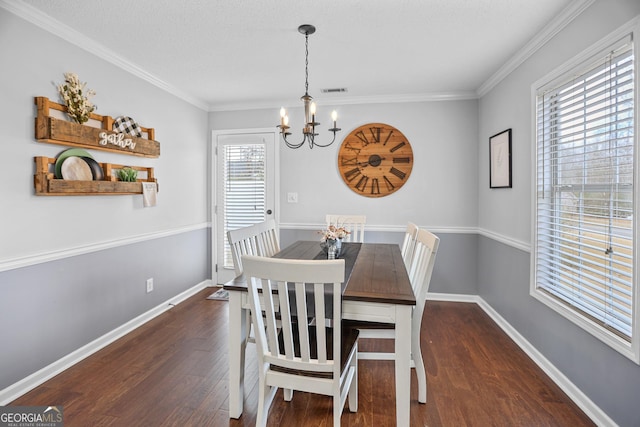 dining space with crown molding, visible vents, wood finished floors, baseboards, and a chandelier