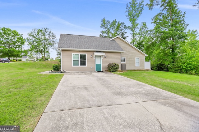 view of front of house with roof with shingles, driveway, and a front yard