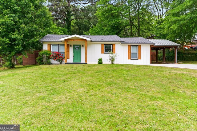 ranch-style house with a front lawn, an attached carport, driveway, fence, and board and batten siding