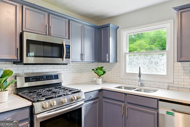 kitchen featuring appliances with stainless steel finishes, tasteful backsplash, a sink, and light countertops