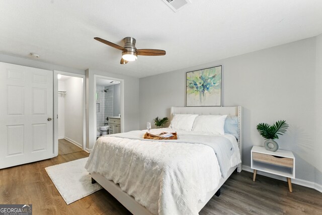 bedroom featuring connected bathroom, baseboards, wood finished floors, and visible vents