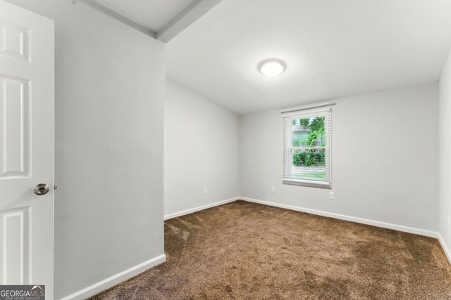 unfurnished room with baseboards and dark colored carpet