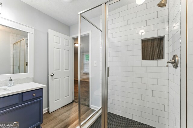 full bath with vanity, wood finished floors, and a stall shower