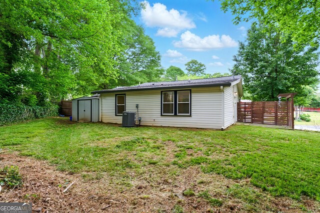 back of property with a fenced backyard, an outbuilding, a yard, and a shed