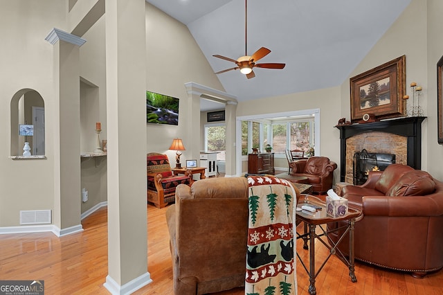 living room with visible vents, wood finished floors, a ceiling fan, high vaulted ceiling, and a stone fireplace