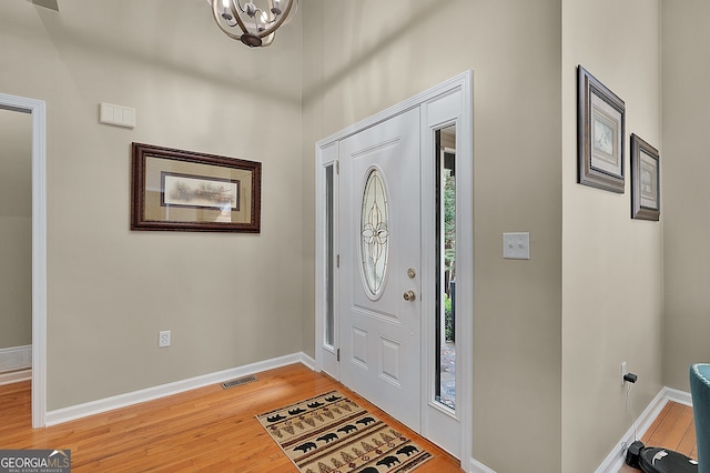 foyer entrance featuring a chandelier, visible vents, light wood finished floors, and baseboards