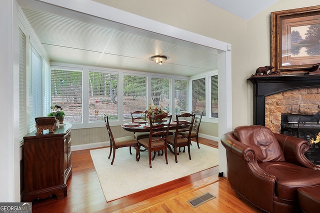 dining area featuring baseboards, visible vents, light wood-style floors, and a fireplace