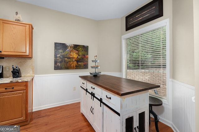 kitchen with wainscoting, butcher block counters, light wood finished floors, and backsplash