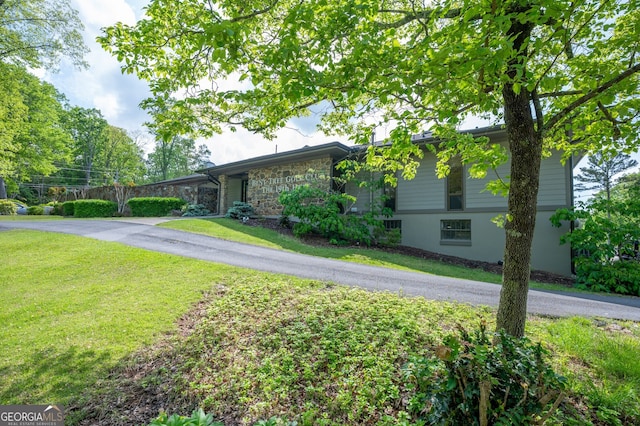 view of front of house featuring stone siding and a front lawn