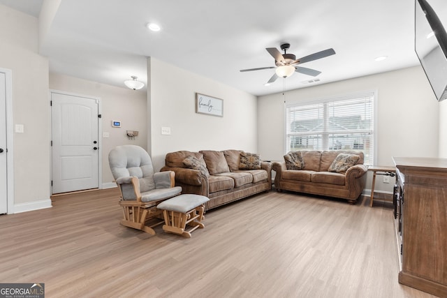 living area with baseboards, light wood-style flooring, visible vents, and ceiling fan