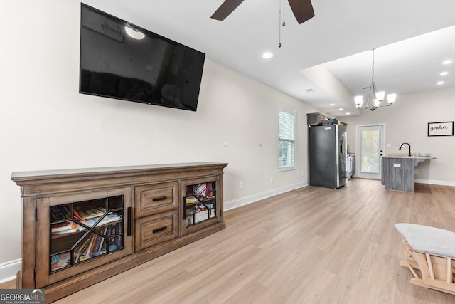 living room featuring ceiling fan with notable chandelier, baseboards, recessed lighting, and light wood-type flooring