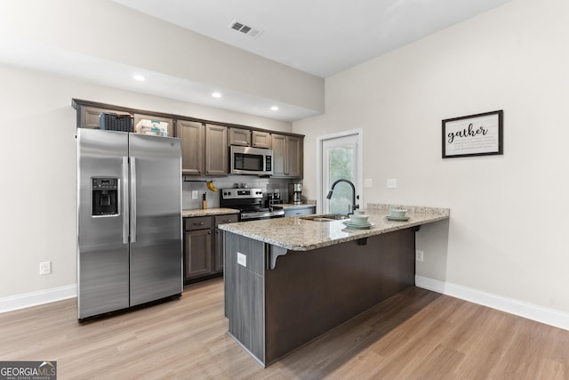 kitchen with a peninsula, light wood finished floors, visible vents, and appliances with stainless steel finishes