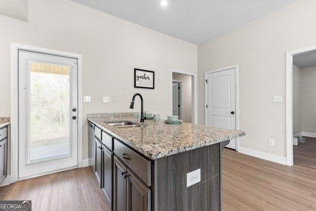 kitchen with a peninsula, baseboards, a sink, and light wood-style floors