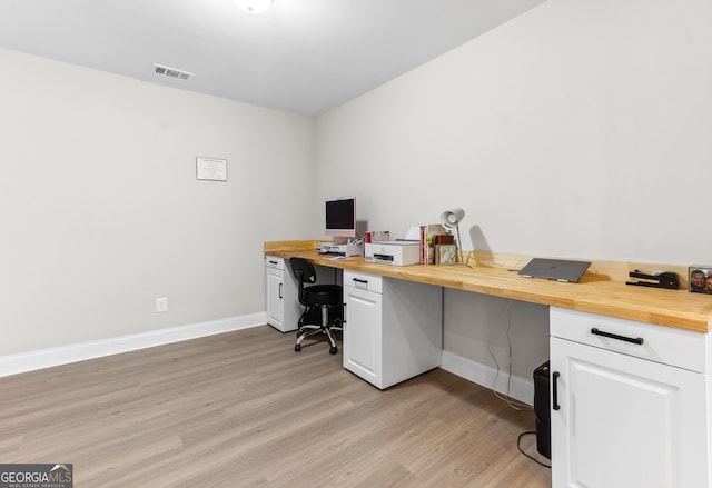 office space with light wood-style floors, visible vents, and baseboards