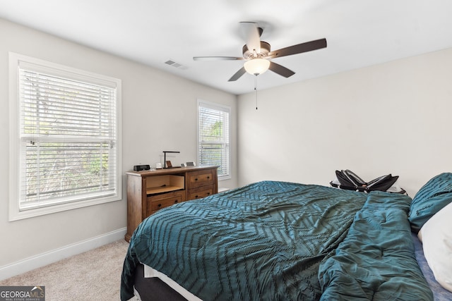 carpeted bedroom featuring baseboards, a ceiling fan, and visible vents