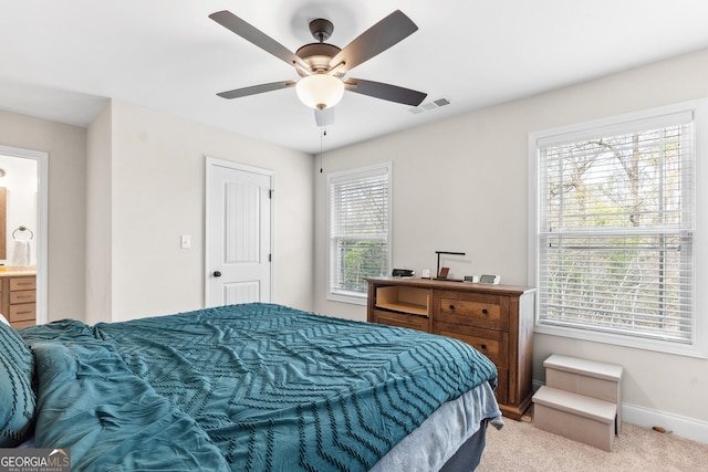 bedroom with a ceiling fan, connected bathroom, light colored carpet, baseboards, and visible vents