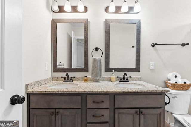 bathroom with a sink, double vanity, and toilet