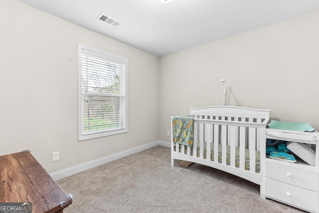 carpeted bedroom with a nursery area, visible vents, and baseboards