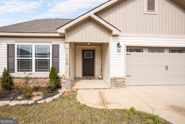 doorway to property with an attached garage, brick siding, driveway, and a shingled roof