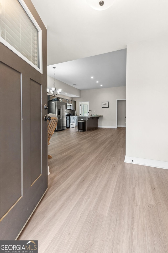living room with a chandelier, light wood-type flooring, and baseboards