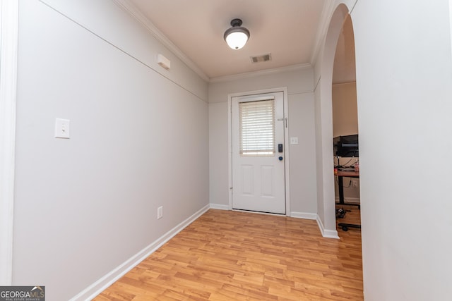 foyer entrance with visible vents, crown molding, arched walkways, baseboards, and light wood-style flooring