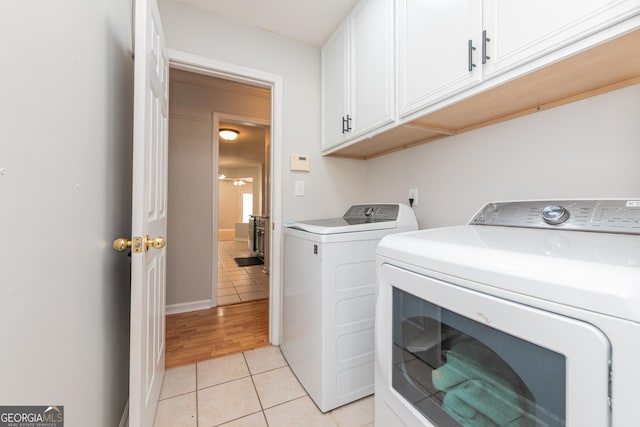washroom featuring separate washer and dryer, cabinet space, and light tile patterned flooring