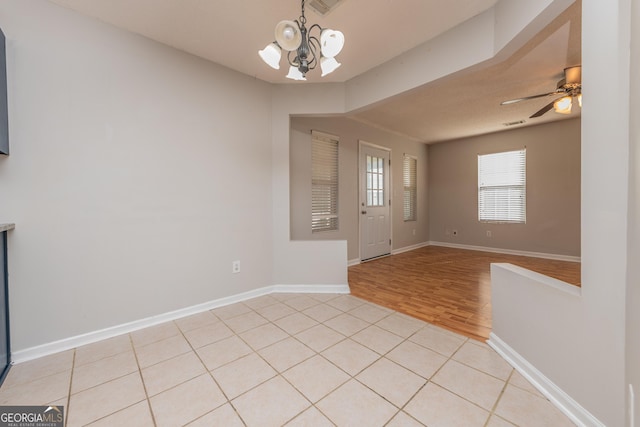 entrance foyer featuring baseboards, ceiling fan with notable chandelier, light wood-style flooring, and visible vents