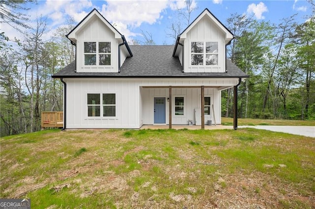 modern farmhouse style home featuring a porch, roof with shingles, a front yard, and board and batten siding