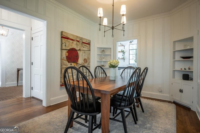 dining space with dark wood-type flooring, ornamental molding, a notable chandelier, and built in features