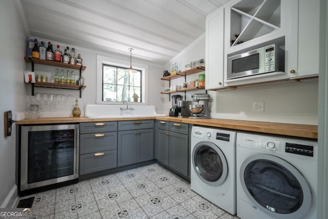 laundry area with light tile patterned floors, ornamental molding, a bar, washer and clothes dryer, and wine cooler