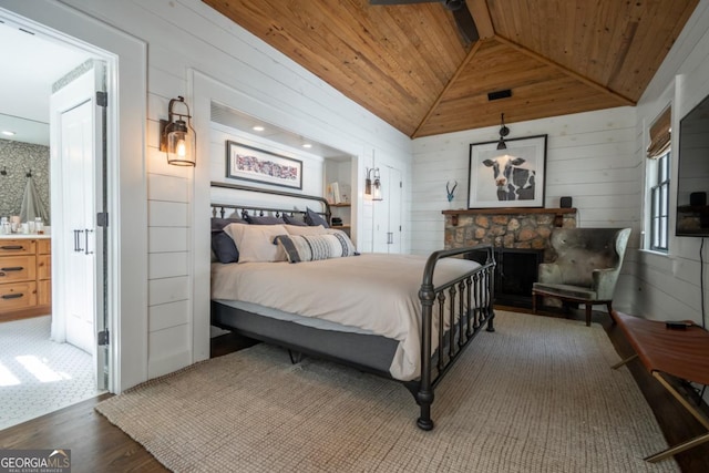 bedroom with wooden ceiling, wooden walls, vaulted ceiling, a fireplace, and wood finished floors