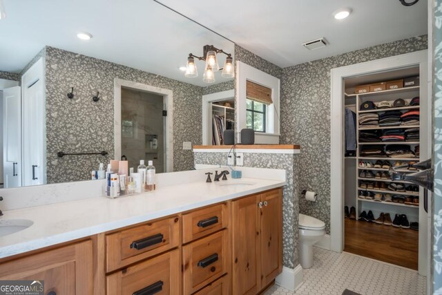 bathroom featuring tile patterned floors, a shower stall, double vanity, a sink, and visible vents