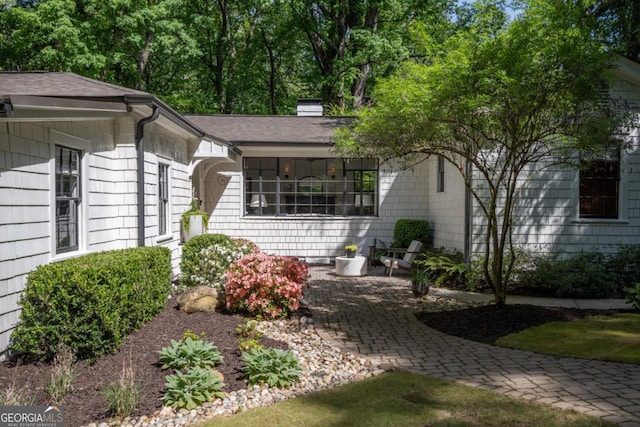 exterior space with a shingled roof and a patio area