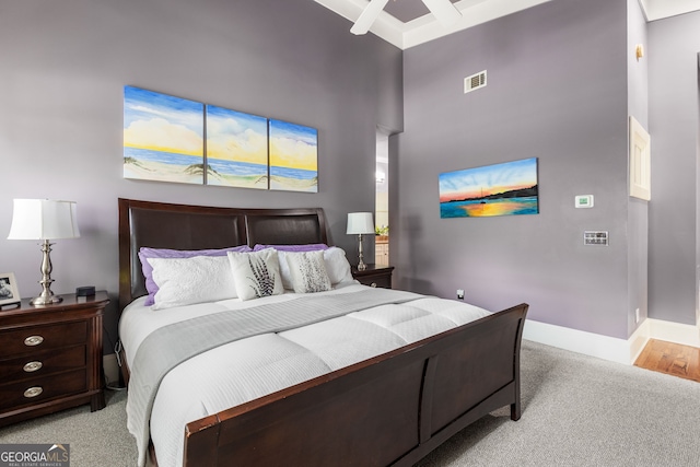 bedroom featuring a towering ceiling, visible vents, baseboards, and light carpet