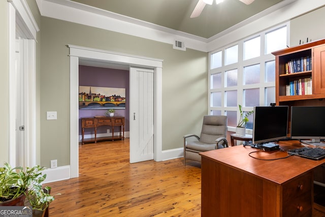 home office with light wood-style floors, ceiling fan, visible vents, and baseboards