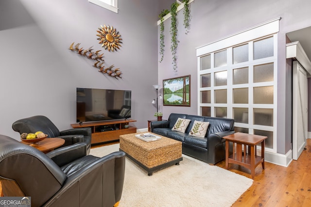 living room featuring light wood-style flooring and a high ceiling