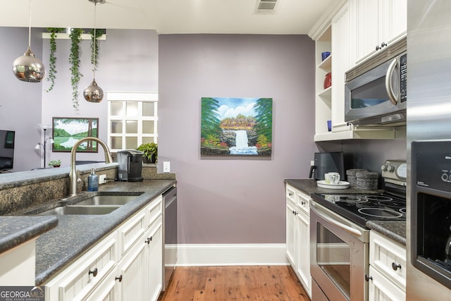 kitchen featuring a sink, visible vents, stainless steel appliances, baseboards, and light wood-type flooring