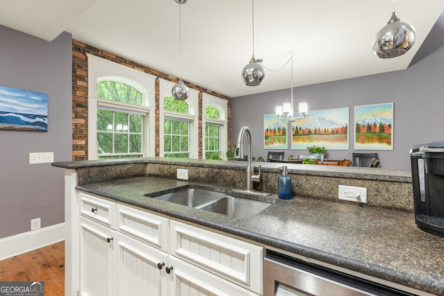 kitchen with a sink, decorative light fixtures, baseboards, white cabinets, and wood finished floors