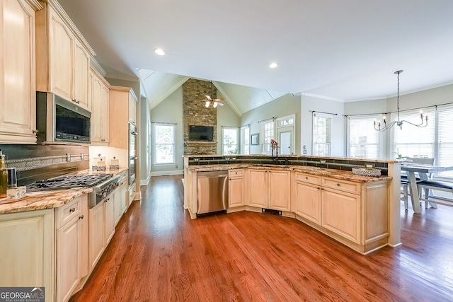 kitchen with wood finished floors, a sink, appliances with stainless steel finishes, open floor plan, and a notable chandelier