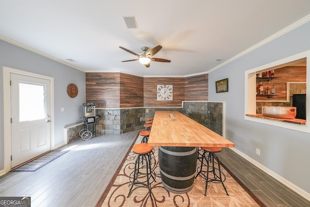 dining room with baseboards, wood finished floors, ceiling fan, and crown molding