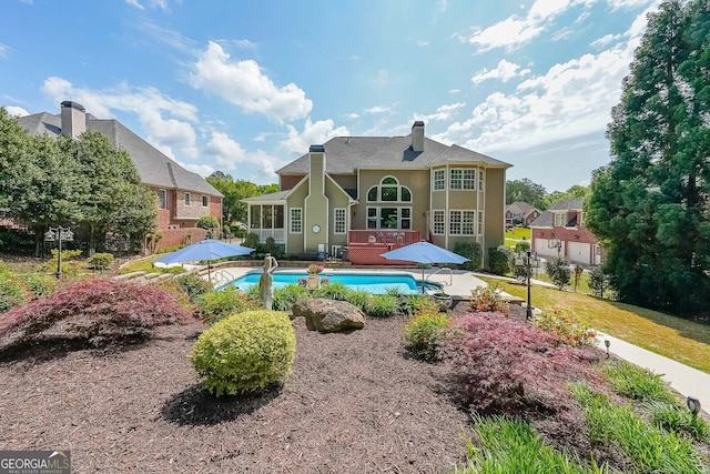 back of property with a patio, a chimney, and an outdoor pool
