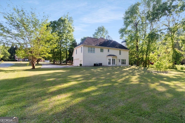 back of property with a garage, a lawn, and french doors