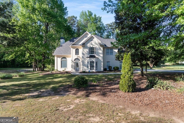 view of front facade with a chimney and a front lawn