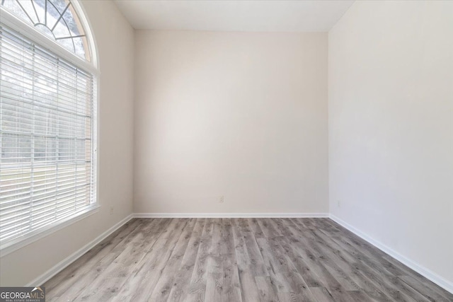 spare room with plenty of natural light, light wood-style floors, and baseboards