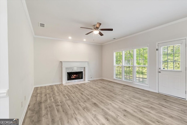 unfurnished living room featuring light wood-type flooring, ornamental molding, ceiling fan, baseboards, and a premium fireplace