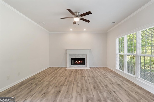 unfurnished living room featuring light wood finished floors, ornamental molding, baseboards, a ceiling fan, and a fireplace
