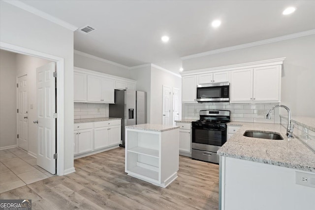 kitchen with stainless steel appliances, a sink, crown molding, tasteful backsplash, and white cabinetry