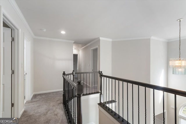 hall featuring an upstairs landing, carpet, a chandelier, ornamental molding, and baseboards