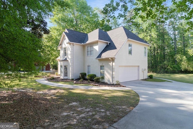 view of front facade with driveway, roof with shingles, a garage, stucco siding, and a front yard