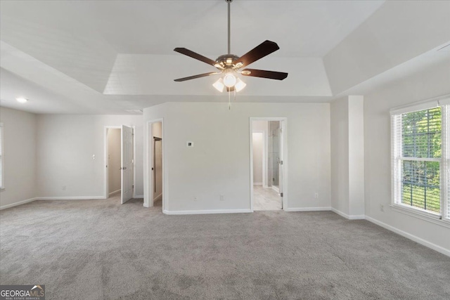 unfurnished bedroom featuring carpet floors, baseboards, and a raised ceiling